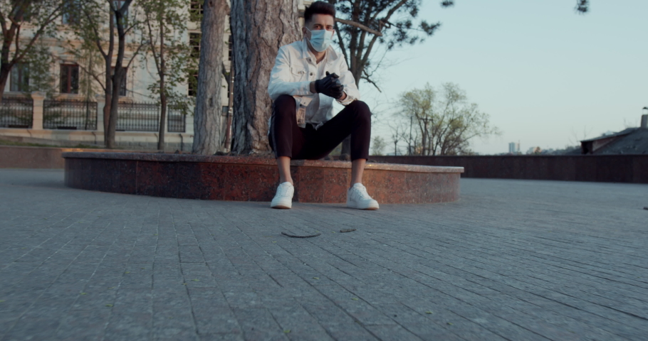 young man, stylish, in a white jacket, with a face mask on his face, in the city