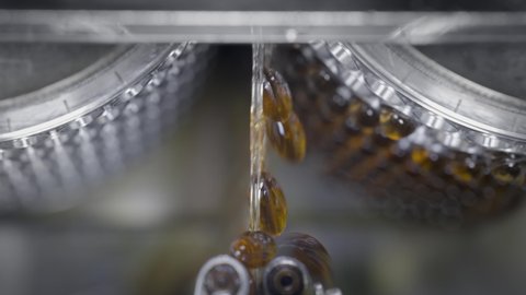 Yellow gel capsules in an automatic machine. Production of dietary supplements and medicines. Tablets with vitamins and minerals for a healthy lifestyle. Omega 3 or fish oil is spinning.