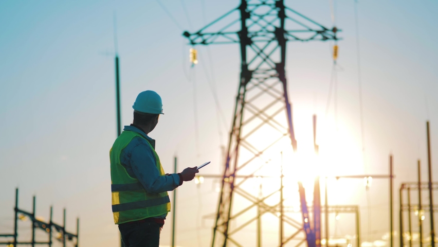 Industry energy business concept. Silhouette electrical engineer a working near tower with electricity at sunset time. Electrical worker inspect voltage electricity pylon. Power generation industry. Royalty-Free Stock Footage #1072020901