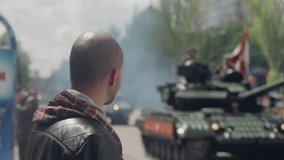 A man watches tanks moving through the city during a military parade - Powered by Shutterstock - Get 15% off with code: PIKWIZARD15
