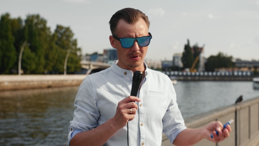 A man wearing sunglasses speaks into a microphone. Preparing for the interview. Medium Shot