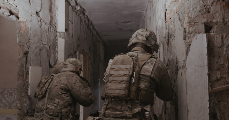 Two soldiers move along the corridor in search of terrorists, one of them steps on a mine and it explodes, gets contusion and severe burns. Concept: Anti-terrorist mission, terrorist attack, military.