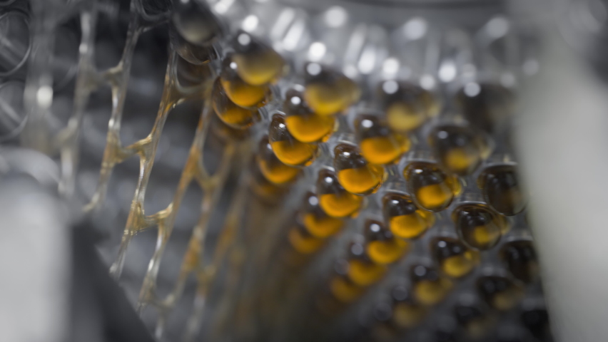Yellow gel capsules in an automatic machine. Production of dietary supplements and medicines. Tablets with vitamins and minerals for a healthy lifestyle. Omega 3 or fish oil is spinning. Royalty-Free Stock Footage #1072032805