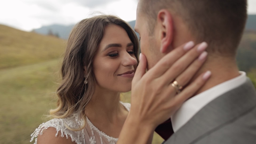 Newlyweds. Lovely young caucasian bride and groom stay together on mountain slope hill. Wedding happy family couple making a kiss. Man and woman in love. Autumn tree. Bride in gorgeous wedding dress