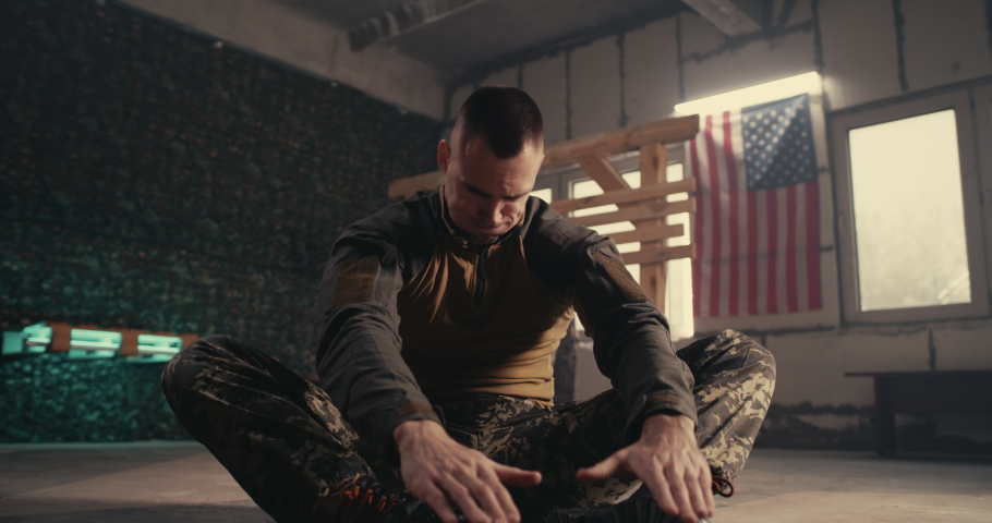 Pan around view of strong male soldier doing abdominal crunches on floor of gym of USA military base