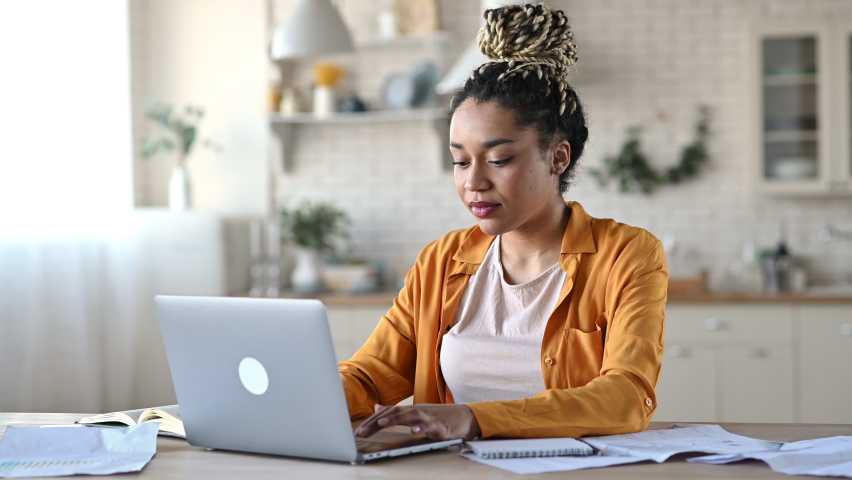 Overjoyed excited african american girl with dreadlocks, freelancer, manager working remotely at home using laptop, looks at screen with surprise, smiling face, gesturing with hands, got a dream job | Shutterstock HD Video #1072044016