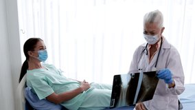 Senior Female doctor explaining the woman patient's results from sick symptoms by X-ray film while lying on a hospital bed. the concept of health, hygiene, treatment, and health insurance.