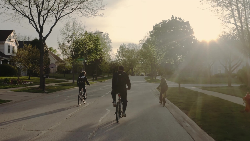 Aerial drone shot of family riding a bike on the streets of the suburbs in sunny weather. Royalty-Free Stock Footage #1072048021