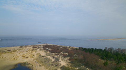 Aerial view showing blue Baltic Sea, sandy beach and natural lake in Mewia Lacha Nature Reserve during summer.