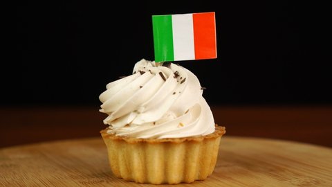 Man places decorative toothpick with flag of Ireland into cream cake. National cuisine