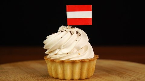 Man places decorative toothpick with flag of Austria into cream cake. National cuisine