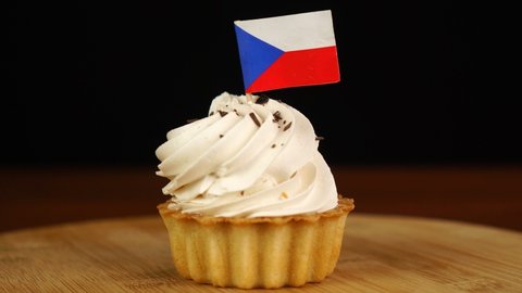 Man places decorative toothpick with flag of Czech Republic into cream cake. National cuisine