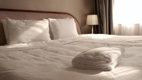 Woman putting a fresh towel on the bed sheet. Room service.