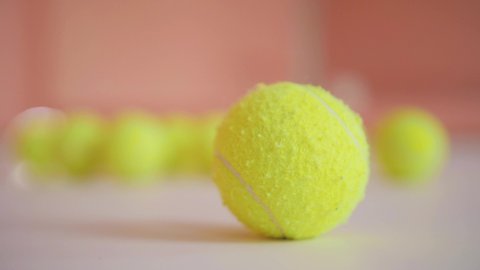 tennis ball close-up on the background of other balls in the training room. Sports equipment for classes and trainings. Many yellow bone balls. An old tennis ball with lint in a clean room.