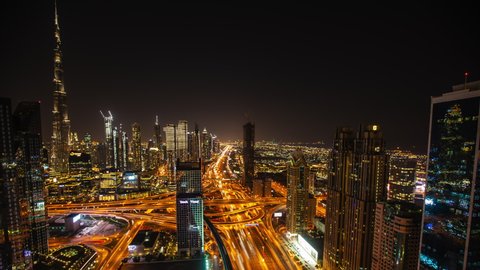 Night timelapse of tall skyscrapers and busy highway traffic in Dubai, UAE. Modern urban city center with Burj Khalifa and multi lane highway traffic at night, Dubai, UAE in 2021
