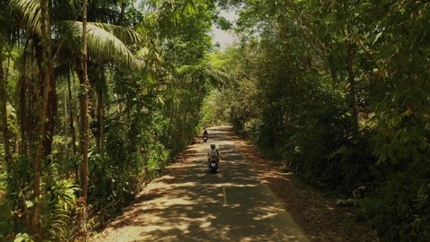 4k top aerial view tourists Thailand. Couple man woman in helmets on motorcycle ride along road in green jungle sunny day. couple people love walking wild jungles together. woman on motorcycle aerial