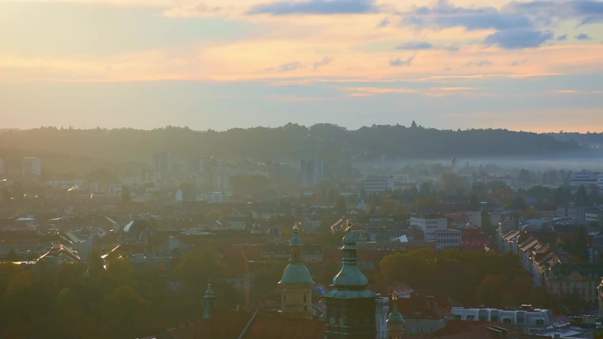 Cityscape of Graz with Church of the Sacred Heart of Jesus and historic buildings rooftops in Graz, Styria region, Austria, at sunrise