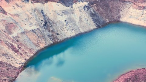 Azure surface of the lake in the technological clay quarry - aerial shot. Blue water lake that originated on the site of a quarry where clay, sand and minerals are mined.
