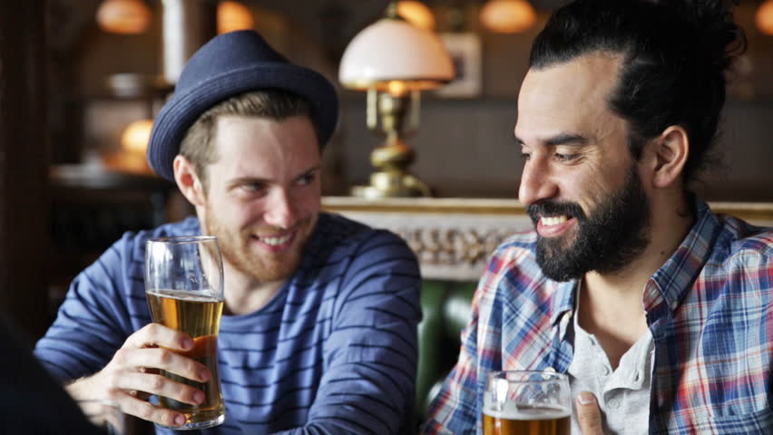 People, toast, leisure, friendship and celebration concept - happy male friends drinking beer and clinking glasses at bar or pub | Shutterstock HD Video #10720748