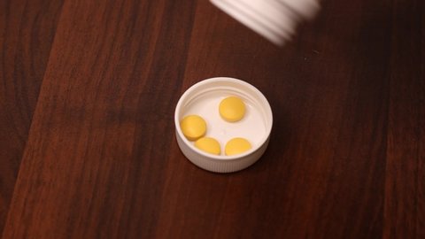 Yellow tablets are poured into the lid of a medical bottle. Daily intake of a complex of vitamins. Maintaining immunity during the coronavirus pandemic. Health care