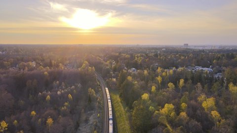 Aerial view of a train passing through the forest during sunset  Concept for train travel  Train travel near munich, germany