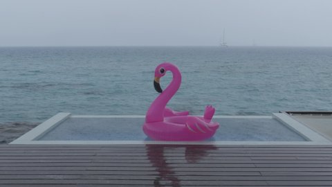 Rain on travel vacation - funny video of flamingo float in luxury pool while raining and bad weather on holidays getaway travel