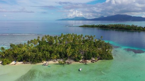 Drone aerial video of Deserted Island paradise. Travel vacation icon of tropical beach private island motu with palm trees. Turquoise crystal clear lagoon ocean water on Bora Bora, French Polynesia