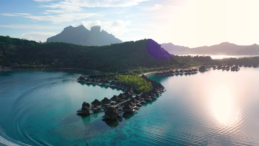 Luxury travel vacation aerial of overwater bungalows resort in coral reef lagoon ocean by beach. Aerial Drone video at sunset paradise getaway Bora Bora, French Polynesia, Tahiti, South Pacific Ocean. Royalty-Free Stock Footage #1072091092