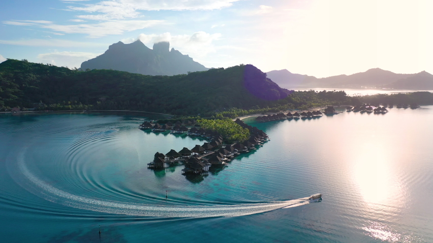 Luxury travel vacation aerial of overwater bungalows resort in coral reef lagoon ocean by beach. Aerial Drone video at sunset paradise getaway Bora Bora, French Polynesia, Tahiti, South Pacific Ocean. | Shutterstock HD Video #1072091092