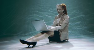 Consulting clients. Young attractive sales expert business woman using laptop webcam video call under water slow motion.