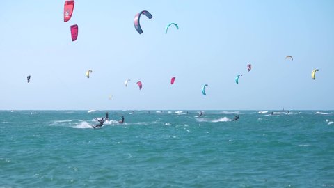 Cabarete, DOMINICAN REPUBLIC - April 20, 2021: Kiteboarding in The Caribbean. Many people ride on the waves on the weekend. Colored parachutes of surfers on the background of blue sky. 