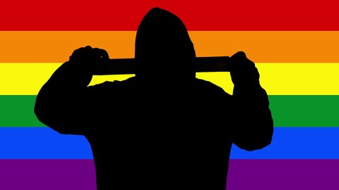 The dark silhouette of a man in a hoodie, over a rainbow LGBT flag, unrolling adhesive tape, coming near the viewer and sealing its mouth or eyes. Symbolic censorship concept.
