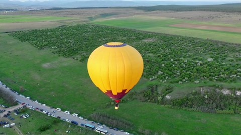 Yellow hot air balloon in the blue sky. Balloon flies over the trees. Beautiful romantic summer scene. aerial view