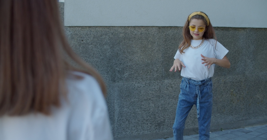 Glamorous girls in sunglasses, jeans and T-shirts dancing stylishly on leisure