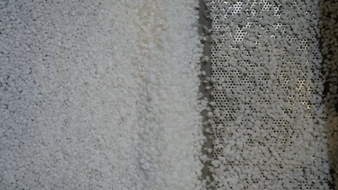 Close up top view: recycled plastic granules - propylene or polyethylene pellets on shale shaker, conveyor belt of waste plastic recycling machine. Separation, ecology, automated technology concept