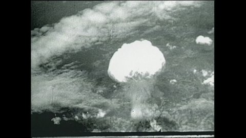 1940s: Mushroom clouds explode into sky. Destroyed city of Nagasaki.