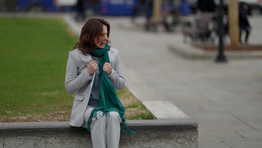 Cool and moody portrait of an adult woman, in slow motion, people pass by in the background.
