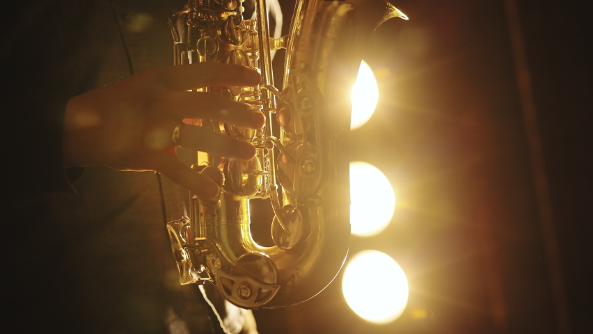 Saxophonist play on golden saxophone. Silhouette of young male saxophonist musician playing golden alt saxophone on musical instrument. Music. Live performance Royalty-Free Stock Footage #1072123076