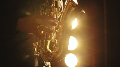 Saxophonist play on golden saxophone. Silhouette of young male saxophonist musician playing golden alt saxophone on musical instrument. Music. Live performance