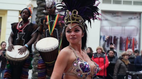 MOSCOW, RUSSIA - FEBRUARY 29, 2020: Celebration of Brazilian carnival. Beautiful girl in colorful festive costume decorated with rhinestones and feathers are dancing samba at street