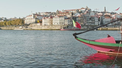 Porto, Portugal. Picturesque city view with traditional boat and old architecture in the background. A small riverside town with tiled buildings as seen from a bank. High quality 4k footage