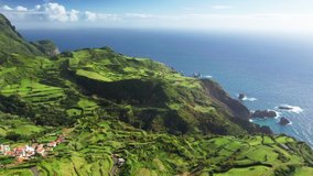 Aerial view of picturesque landscape of Flores Island at sunny day, Azores, Portugal, Europe. Panoramic view of houses surrounding green farm fields at atlantic ocean, 4k footage