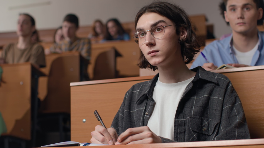Group of students learns at lecture room. Young people study in university or pupil sitting at school lesson. Teen listens to teacher and writes at auditorium. Modern education indoors of college hall - Powered by Shutterstock - Get 15% off with code: PIKWIZARD15