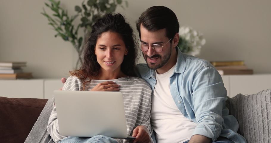 Loving young 30s family couple looking at laptop screen, planning vacation travel, web surfing information, booking hotels or flight tickets online on weekend, resting together on sofa at home. Royalty-Free Stock Footage #1072143404