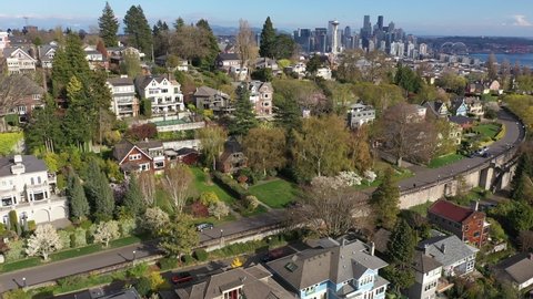 Cinematic trucking drone shot of Marshall Park, Parsons Gardens, West Queen Anne, Lower Queen Anne, downtown Seattle, Mt. Rainier, affluent neighborhoods by Puget Sound, in Washington
