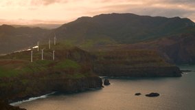Aerial sunset view of wind turbines for electricity production located at the atlantic coast of Madeira, Portugal. Wind power turbines generate clean renewable green energy. 4K UHD video.