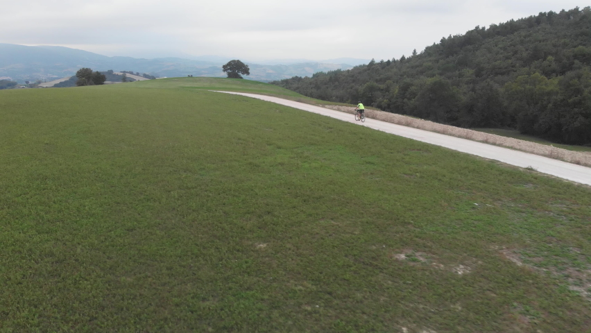 Aerial drone view over a country road with a cyclist