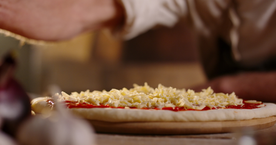 Close up shot of chef putting shredded cheese on pizza dough with tomato sauce. Process of making traditional italian handmade pizza 4k footage Royalty-Free Stock Footage #1072161692