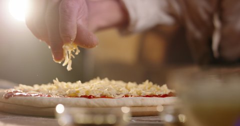Close up shot of chef putting shredded cheese on pizza dough with tomato sauce. Process of making traditional italian handmade pizza 4k footage