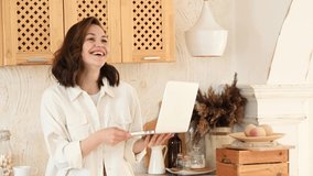 a young attractive woman in a bright modern kitchen uses a laptop for video communication